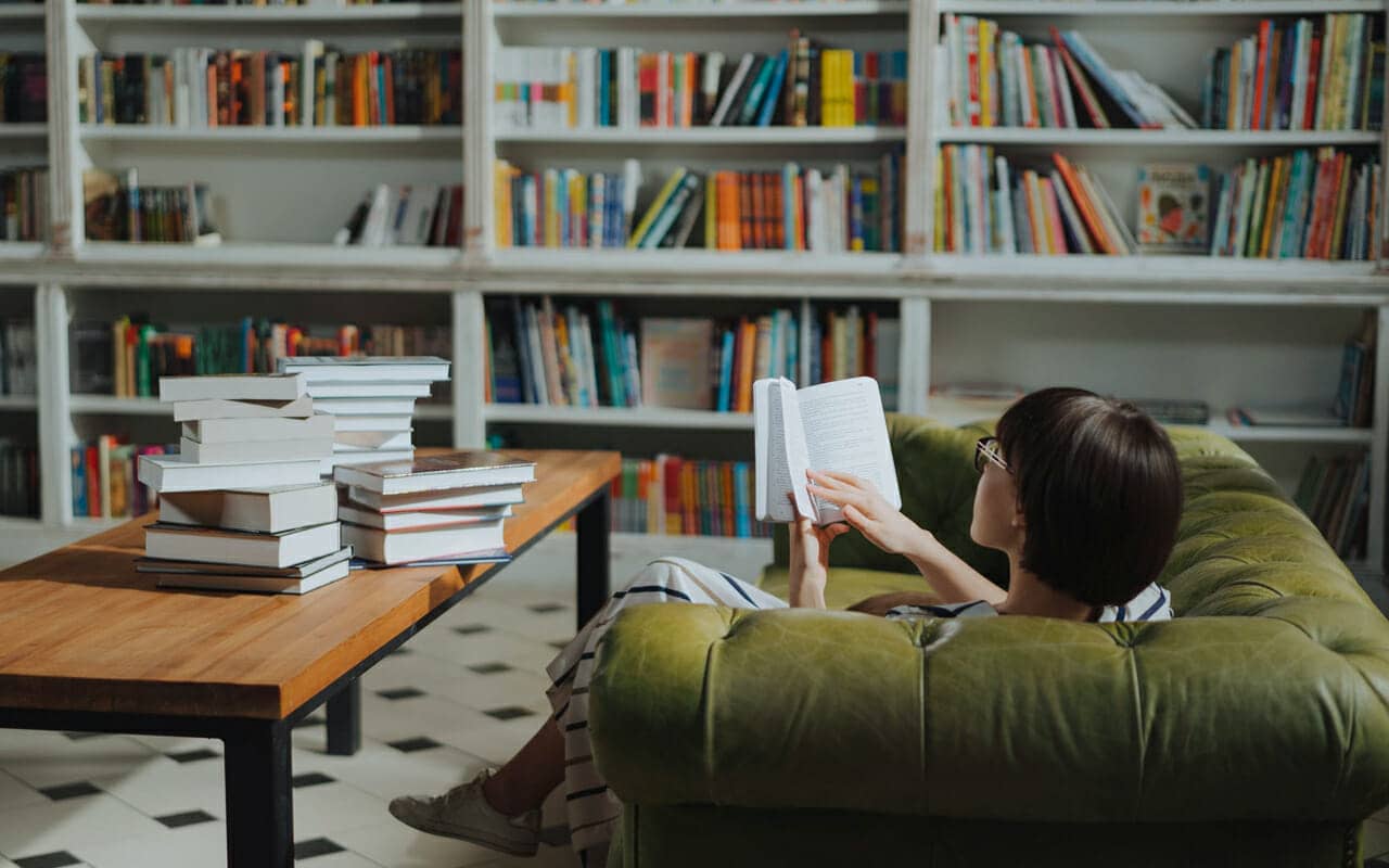 a girl is reading on a green sofa