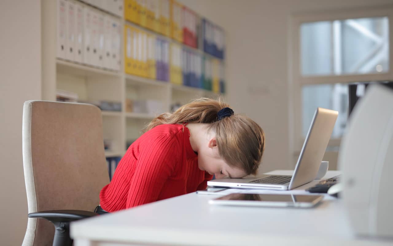 a woman gives up and bangs her head on a laptop