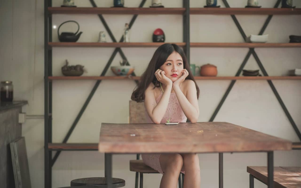 a woman is thinking with her hands on her chin