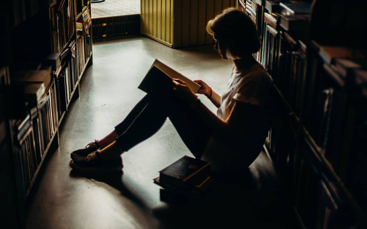 a woman is reading on the floor in a library