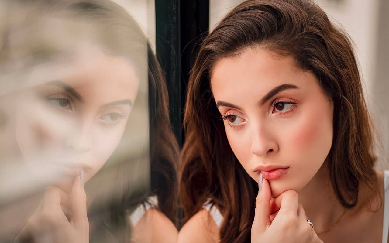 a woman is thinking beside a window