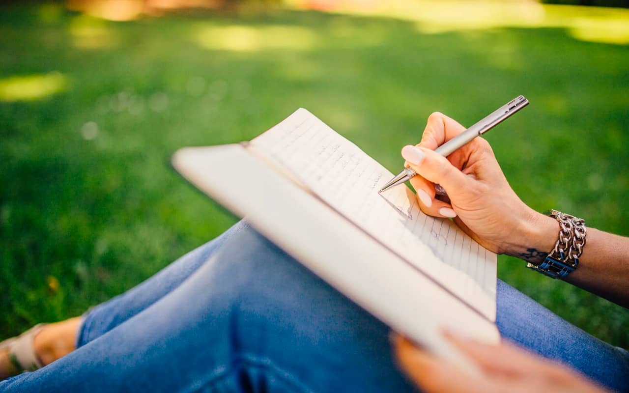 a woman is writing on a journal