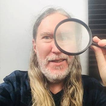 Anthony Metivier with a magnifying glass to demonstrate a concept related to different types of observation and how they relate to memory improvement