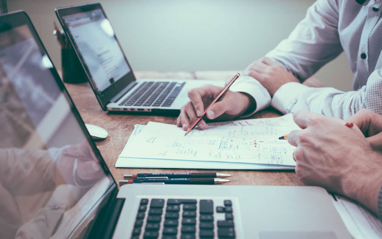 People sit at a table with open laptops and a pad of paper, doing a concentration self-assessment.