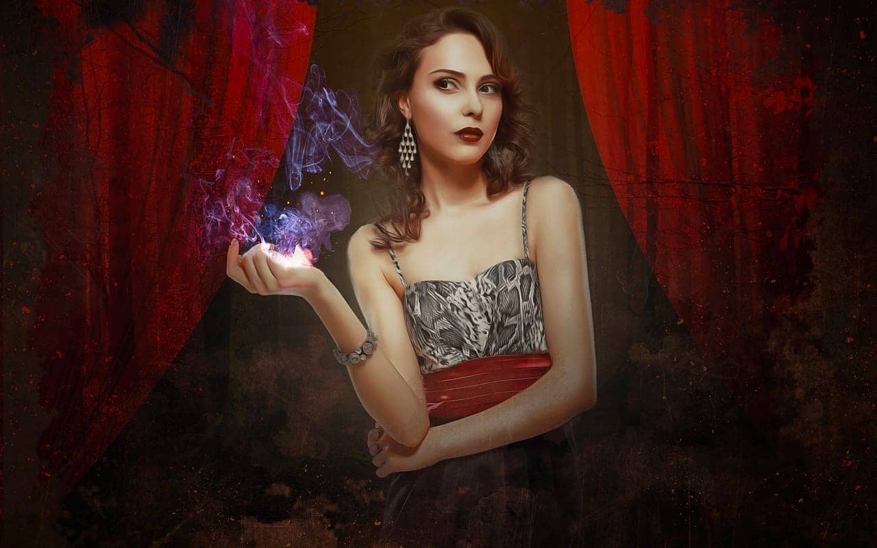 beautiful magician performing in front of a red background