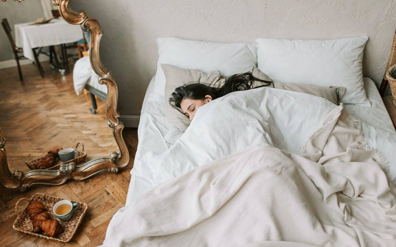black hair woman is sleeping in a white bed