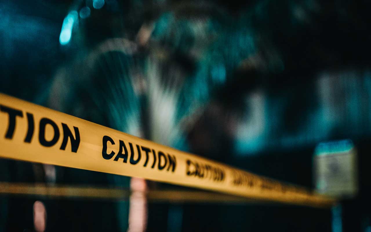 Caution tape stretched across a space, with a blurry background. 