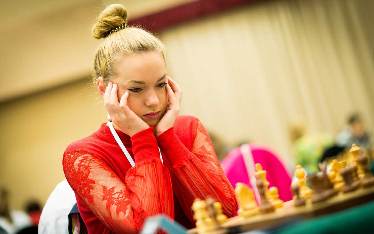 A woman focuses on her next move in a chess game.