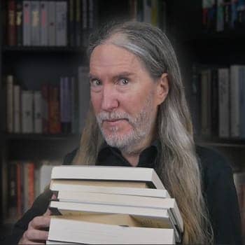 Anthony Metivier with a pile of books to illustrate a concept related to how to deal with information overload