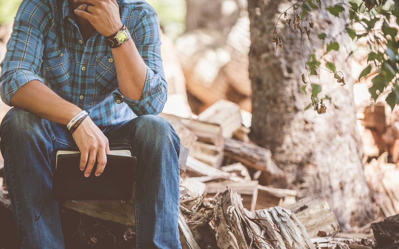 A person sits and contemplates, holding a book in their hand. Setting aside time for reflection is key for your visualization reading strategy.