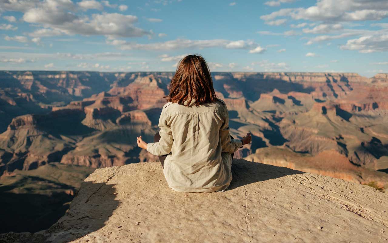A woman meditates outside at the Grand Canyon.