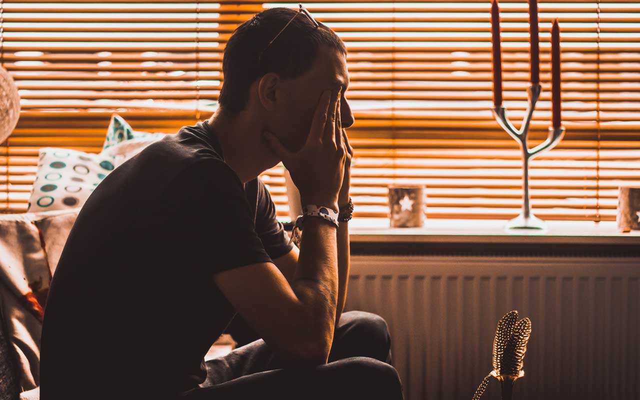 A man sits with his face in his hands.
