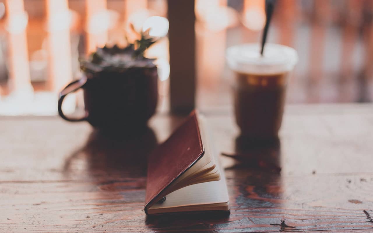 notebook coffee and plant on a desk