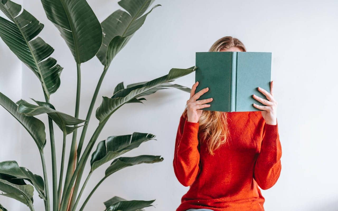 red sweater woman is reading a green book