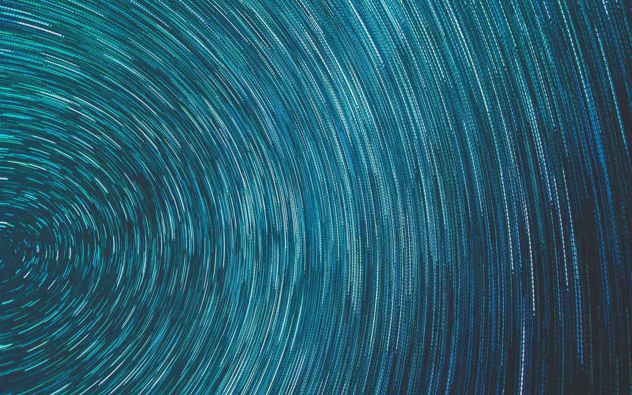 A visual representation of a sound wave, with blue and green circles spinning out from the center.