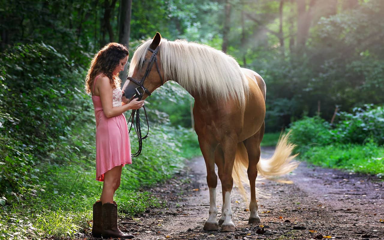 a woman with a horse on the forest path