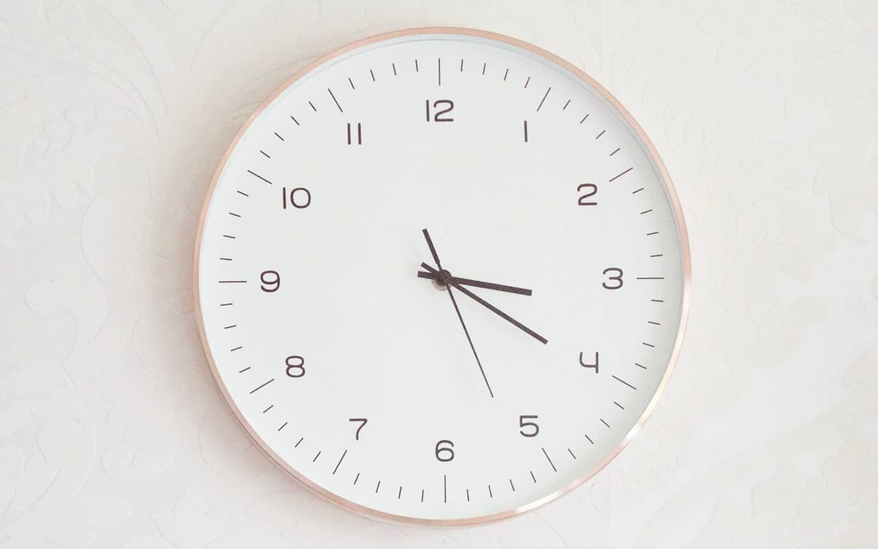 A rose and white colored clock against a white wall. Finding the best time to learn Spanish will be up to you.