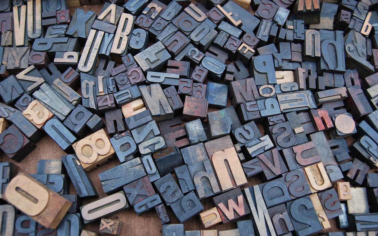 A series of print blocks from a printing press, with numbers and letters in many different shapes and sizes.